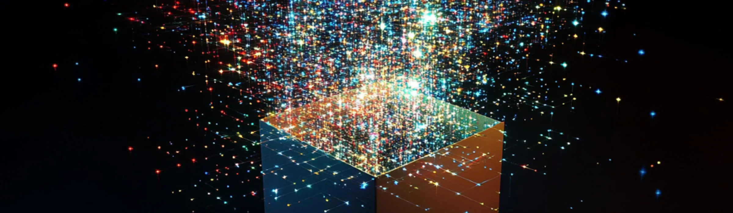 Cube emitting colorful data points, with blue, red, and gold light particles streaming upward against a black background, representing data transformation and AI capabilities.