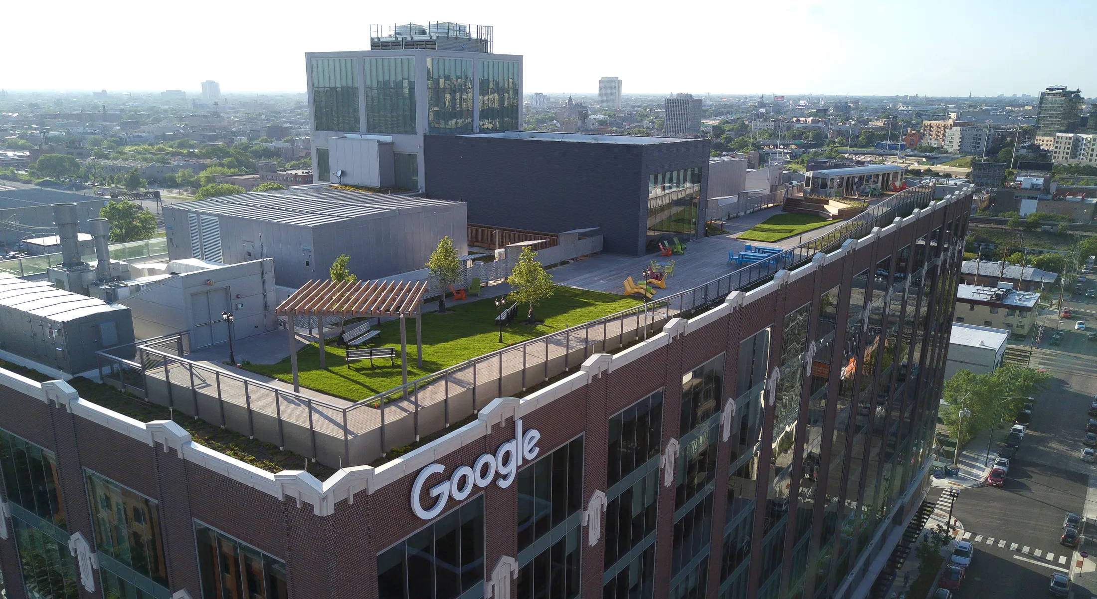 Aerial view of Google Chicago office rooftop with green space, seating areas, and cityscape in the background.