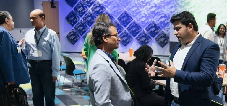 Attendees networking and discussing during AI-enabled experiences event, with colorful background decor.